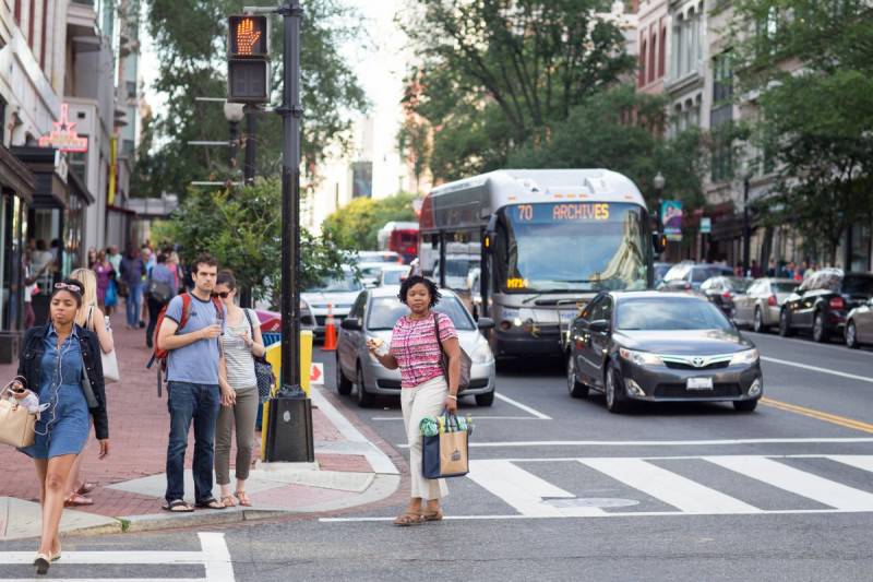 photo of a street corner with various people walking among traffic